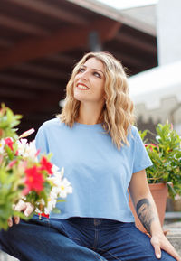 Young women wearing t-shirt and jeans seats between flowers