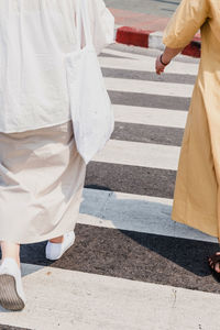 Low section of man and woman walking on crosswalk