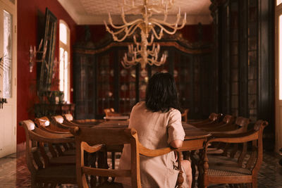 Rear view of woman sitting on chair at home