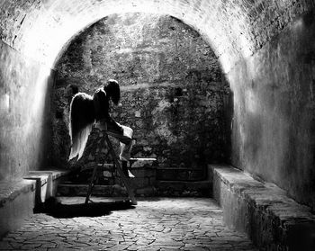 Rear view of woman sitting in corridor