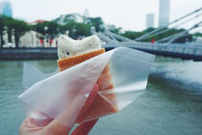 Close-up of hand holding ice cream over river