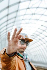 Portrait of man gesturing while standing in greenhouse