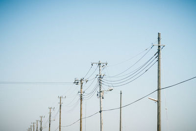 Low angle view of electricity pylon against clear sky