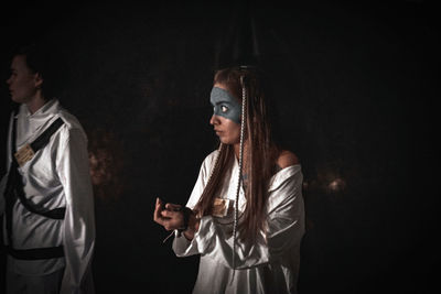 Man and woman standing against black background
