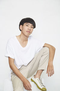 Portrait of young man sitting against white background