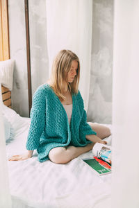 Woman sitting on bed at home