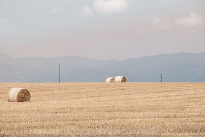 Hay bales on field against sky