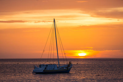 Sailboat on sea against romantic sky at sunset