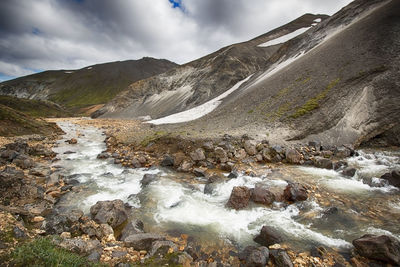 Stream flowing by mountains at landmannalaugar in winter