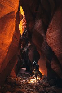 Rear view of man standing by rock formations in cave