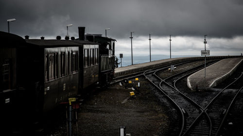 Railroad tracks at station against cloudy sky