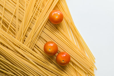 Close-up of spaghetti and tomatoes against white background