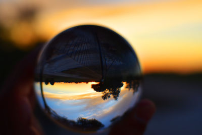 Close-up of hand against orange sky