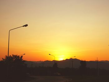 Silhouette street lights against orange sky