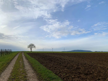 Road amidst field against sky