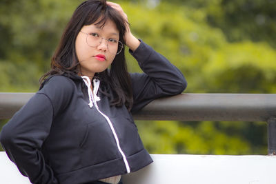 Young woman looking down while standing against railing