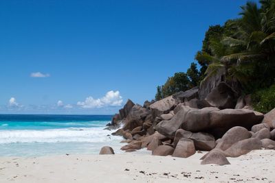 Rocks on beach against clear blue sky