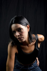 Portrait of young woman against black background