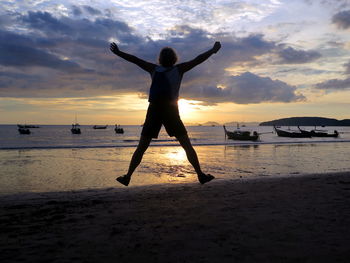 Silhouette man standing on beach against sky during sunset