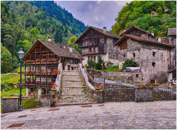 Old house by building against sky