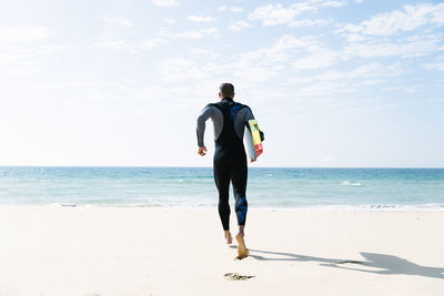 Rear view of man on beach against sky