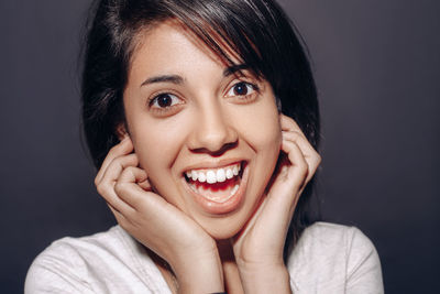 Portrait of cheerful young woman gesturing against gray background