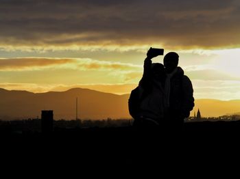 Man photographing against sky during sunset