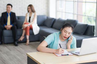 Young woman using phone while sitting on table