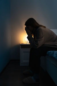 Depressed woman sitting on bed at home