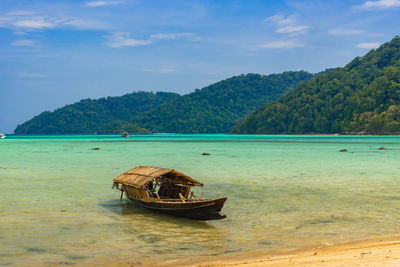 Thailand nature landscape. a long tail boat by the beach in thailand green mountains and blue sky