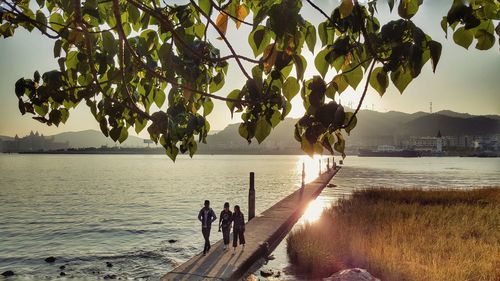 Friends walking on jetty by river