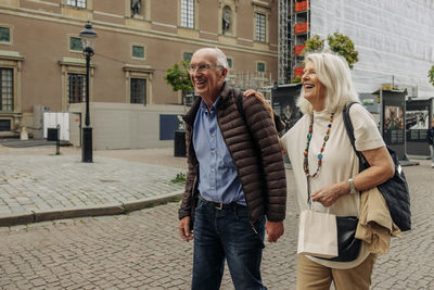 Happy retired senior couple walking on street in city