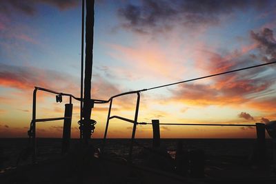 Silhouette poles on beach against sky during sunset