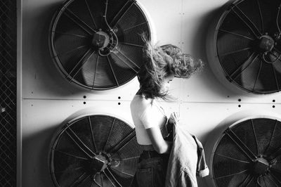 Woman with umbrella on bicycle against wall