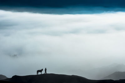 Silhouette people on mountain against sky