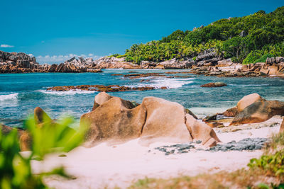 Rocks on beach against blue sky