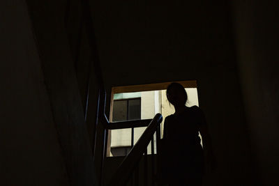 Silhouette of a woman standing by window at staircase