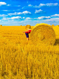 Person standing by hay bale on agricultural field