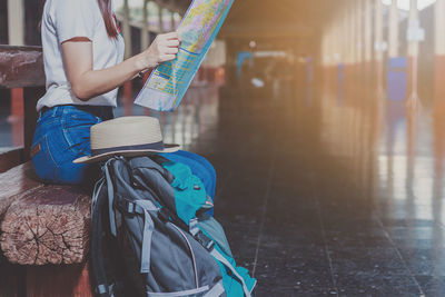 Midsection of woman reading map at railroad station platform