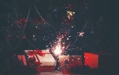 Close-up of illuminated sparkler by christmas tree at night