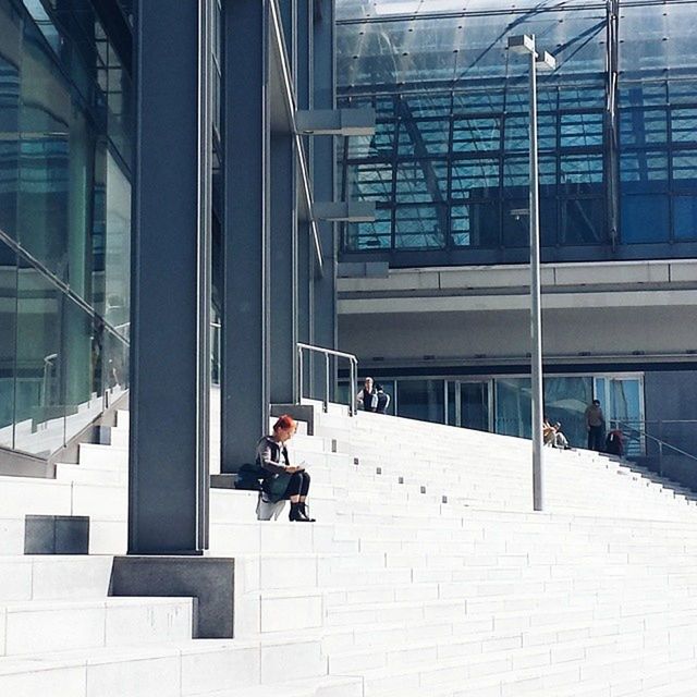 architecture, built structure, building exterior, men, lifestyles, window, glass - material, leisure activity, city, full length, person, building, sitting, reflection, modern, day, rear view