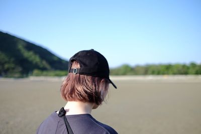 Rear view of woman wearing cap against clear sky at beach