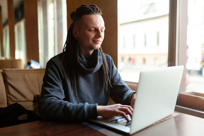 Hipster man using laptop in cafe