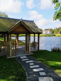 Gazebo by lake against sky