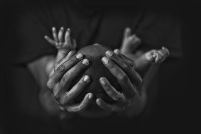 Midsection of mother carrying baby against black background