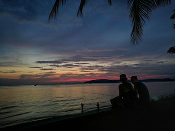 Silhouette people on beach against sky during sunset