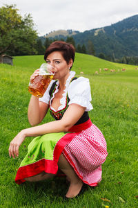 Beautiful young woman sitting on grass in field