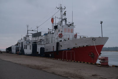 Ship moored at harbor against sky