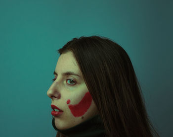 Close-up of young woman with face paint against colored background