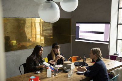 Businesswoman with female colleagues discussing over color swatch in conference room